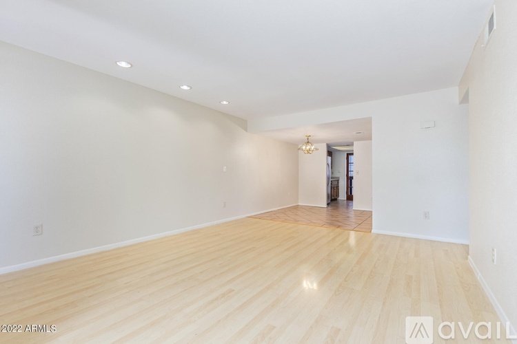 A spacious room with wooden flooring and white walls.