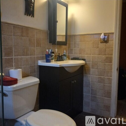 A bathroom with a toilet, sink, and mirror.