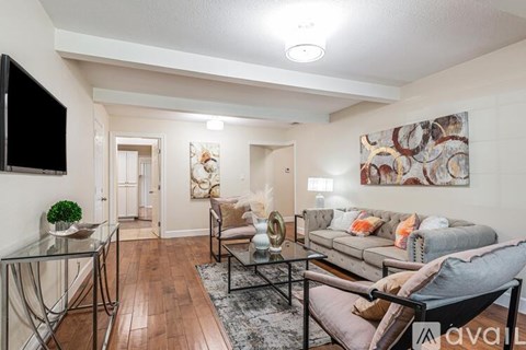 A living room with a glass table and a grey couch.