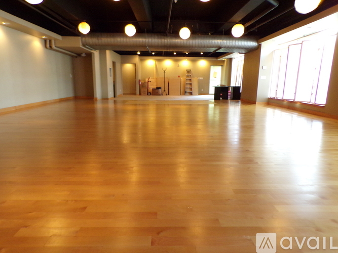 A spacious room with wooden flooring and a high ceiling.