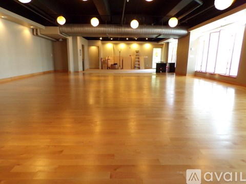 A spacious room with wooden flooring and a high ceiling.