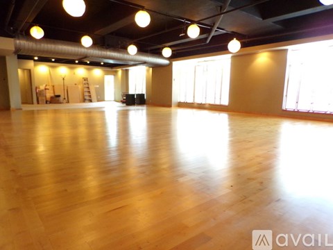 A spacious room with wooden floors and large windows.