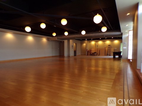 A spacious room with wooden floors and ceiling lights.