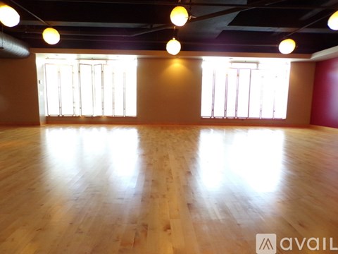 A spacious room with wooden flooring and windows letting in natural light.