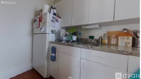 A kitchen with white cabinets and a refrigerator with magnets on it.