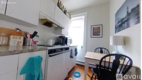 A kitchen with white cabinets and a black chair.