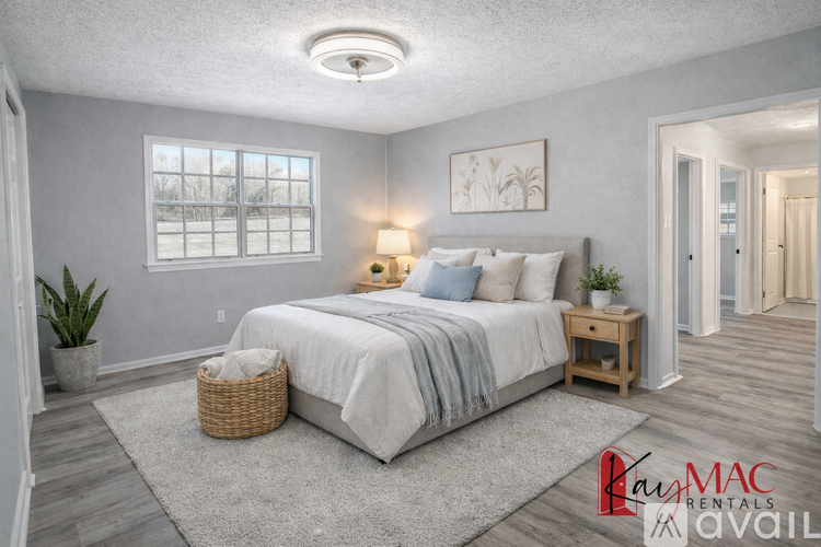 A well-lit bedroom with a large bed, a nightstand, and a window.