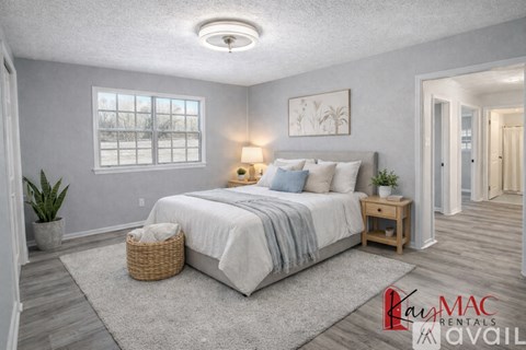 A well-lit bedroom with a large bed, a nightstand, and a window.