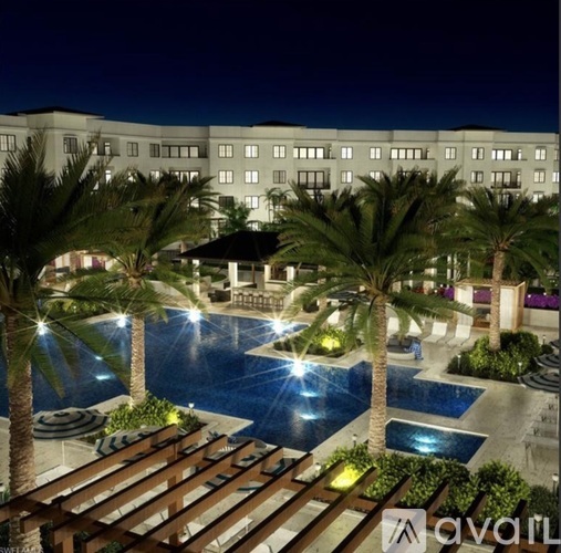 A hotel at night with a pool and palm trees.