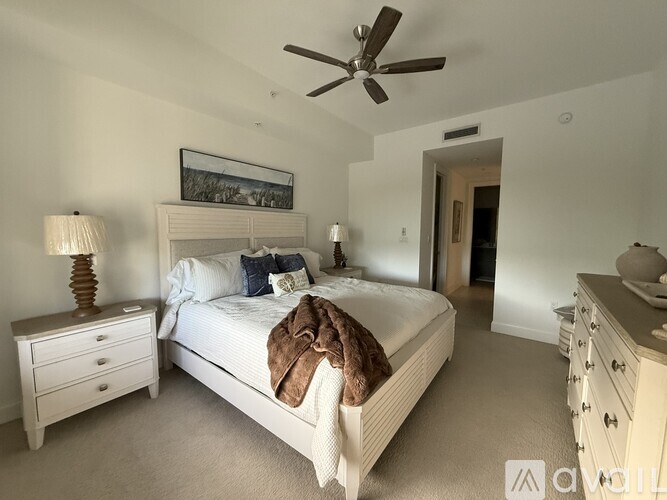 A bedroom with a large bed, a ceiling fan, and a dresser with a mirror.