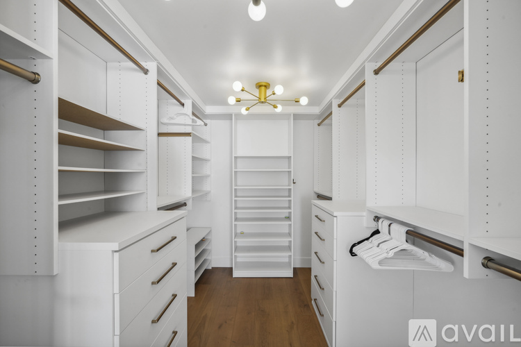 A spacious walk-in closet with white shelves and drawers.