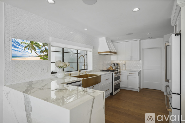 A modern kitchen with white cabinets and a marble countertop.