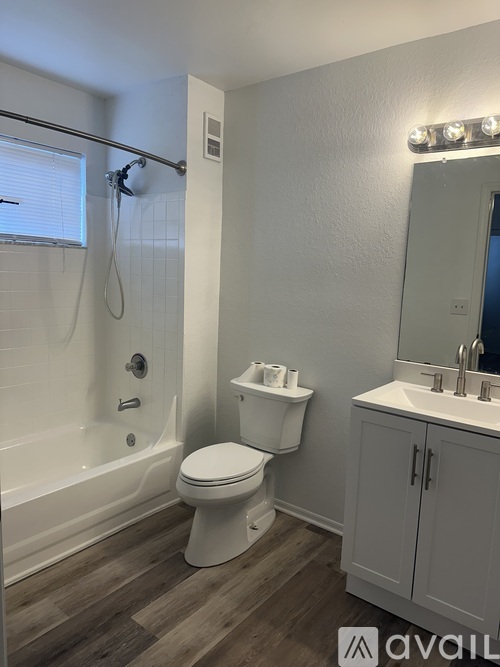 A white toilet sits in a bathroom next to a sink and a bathtub.