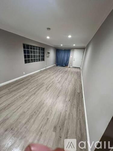 A room with wooden flooring and a window with a blue curtain.