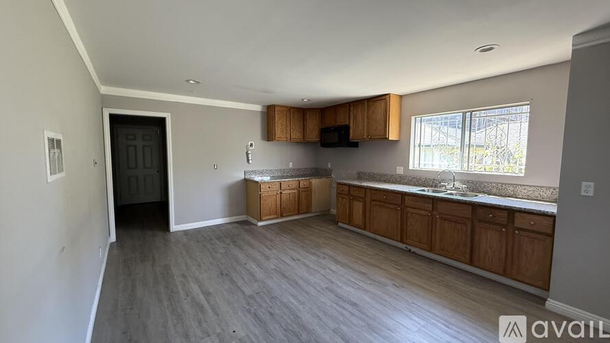 A spacious kitchen with wooden cabinets and a window.