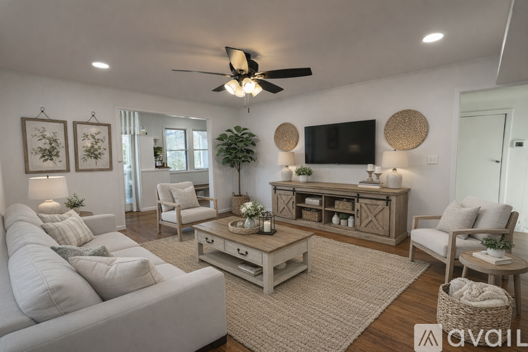 A living room with a white couch, a wooden coffee table, and a flat-screen TV mounted on the wall.