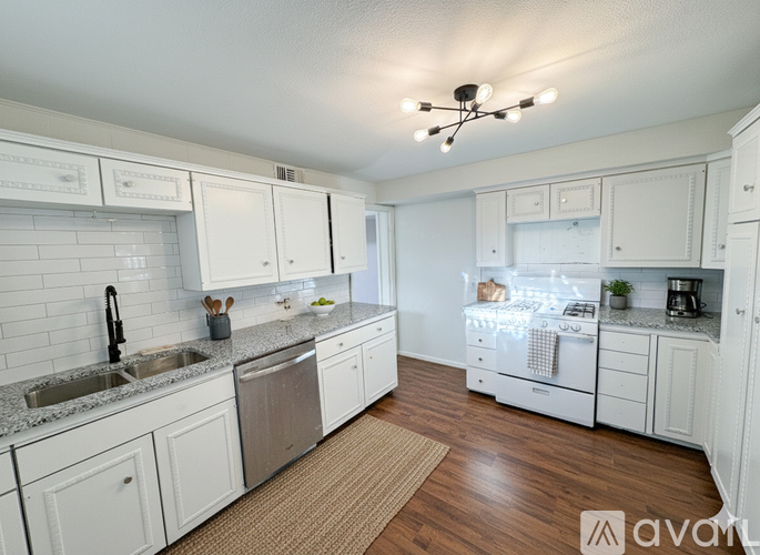 A kitchen with white cabinets and a wooden floor.