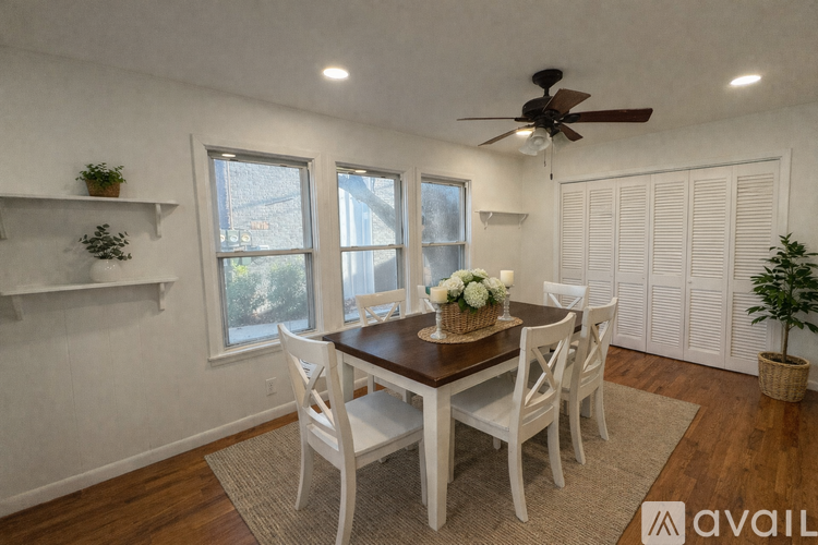 A dining room with a wooden table and white chairs.