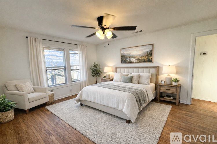A bedroom with a large bed, a chair, and a painting on the wall.