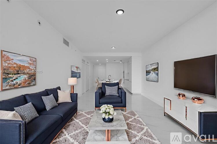 A living room with a blue sofa and a grey rug.