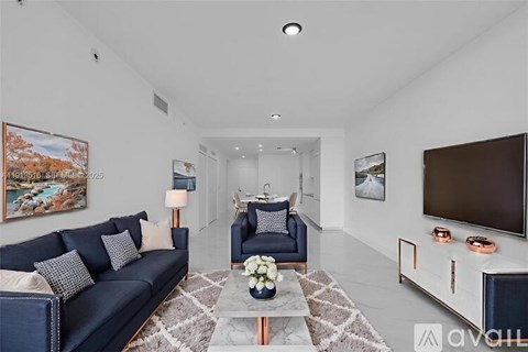 A living room with a blue sofa and a grey rug.