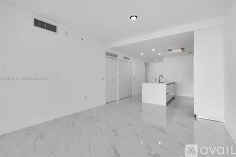 A spacious, empty room with a marble floor and white walls.