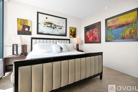 A bedroom with a large bed and four paintings on the wall.
