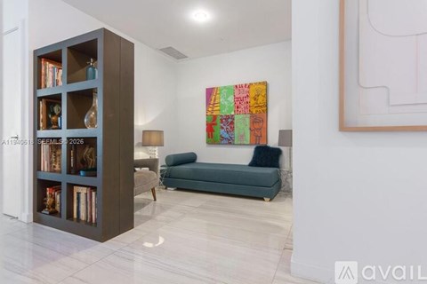 A living room with a bookshelf, a couch, and a painting on the wall.