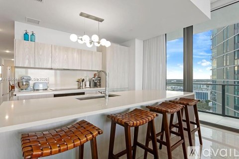 A modern kitchen with a bar stool in front of the counter.