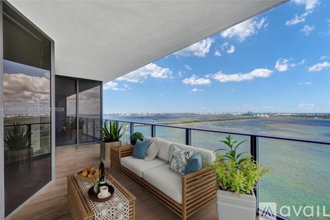 A balcony with a couch, table, and plants overlooking a body of water.
