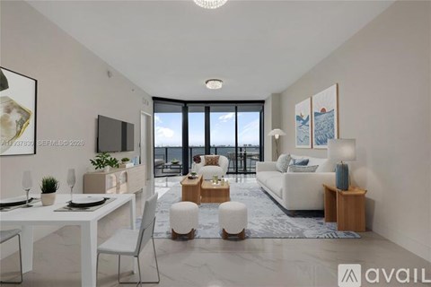 A modern living room with a dining table and a large window overlooking the sea.