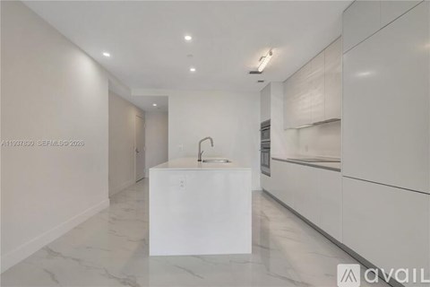 A modern kitchen with a white island in the middle.