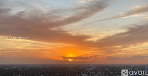 A sunset over a cityscape with the sun just touching the horizon.
