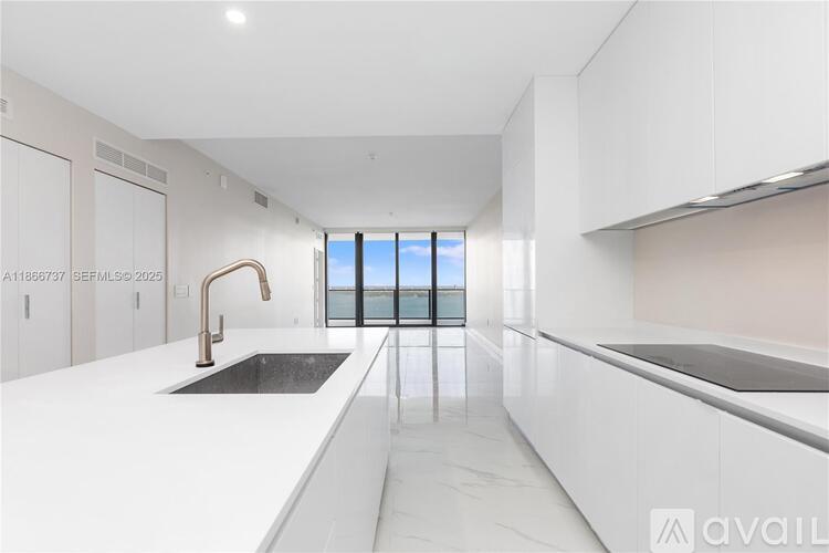 A modern kitchen with white cabinets and a black countertop.