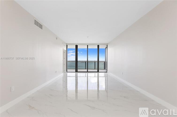 A spacious room with a marble floor and a window overlooking the beach.