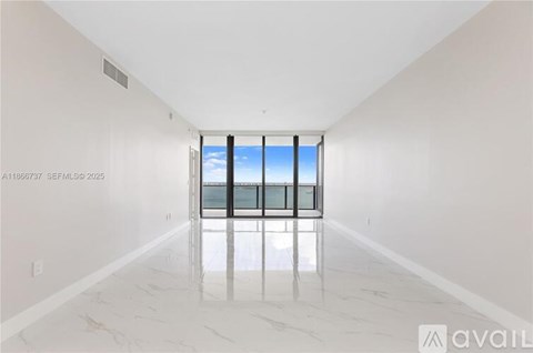 A spacious room with a marble floor and a window overlooking the beach.