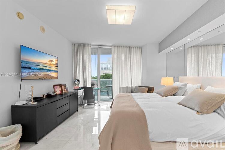 A modern bedroom with a large bed and a flat-screen TV mounted on the wall.