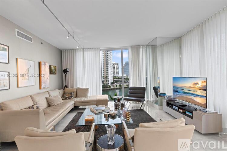 A living room with a large couch, a coffee table, and a television.