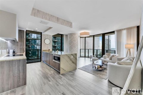 A modern kitchen with a large island and a living area with a couch and chairs.
