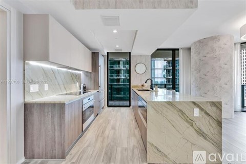 A modern kitchen with a marble countertop and wooden flooring.