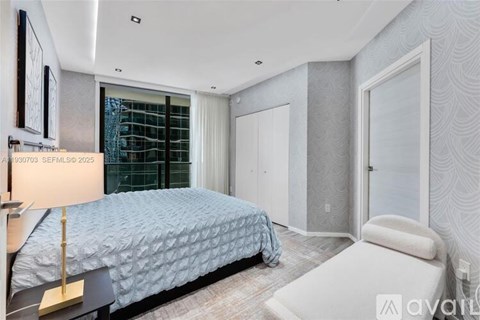 A bedroom with a bed, a chair, and a lamp.