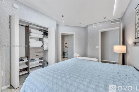 A bedroom with a large bed and a white wall.
