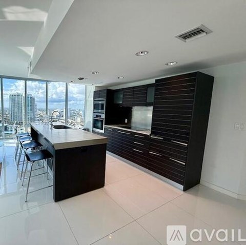 A modern kitchen with a bar area and a view of the city.