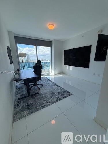 A person is sitting on a black chair in a room with a large window.