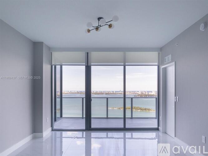 A spacious room with a ceiling fan and a view of the water.