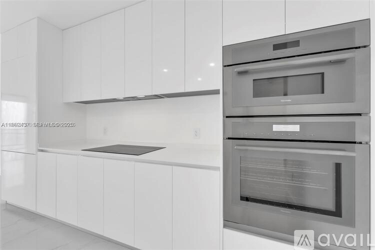 A modern kitchen with white cabinets and stainless steel appliances.