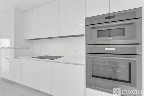 A modern kitchen with white cabinets and stainless steel appliances.