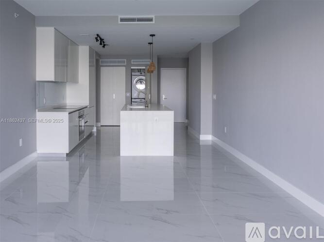 A spacious kitchen and living room with white cabinets and a marble floor.