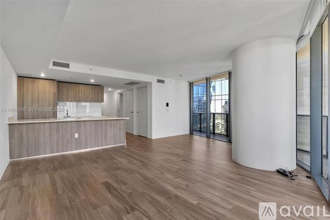 A spacious room with wooden flooring and a bar area.