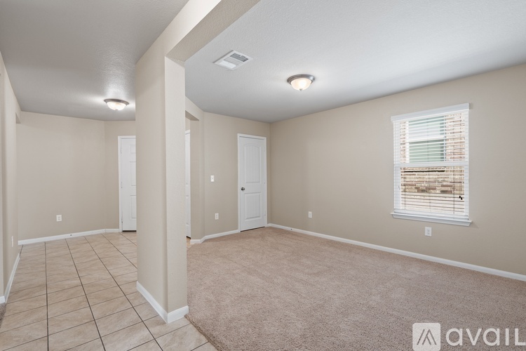 A spacious room with beige walls and a window with blinds.